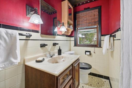 Main-level bathroom features classic tile walls with contrasting black accents, and a vanity with storage.