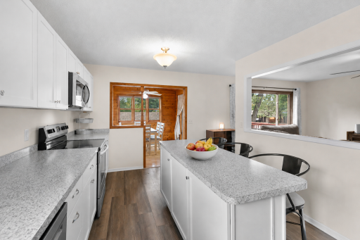 Bright and inviting kitchen featuring crisp white cabinetry, beautiful countertops, stainless steel appliances, and a spacious center island with breakfast-bar seating.