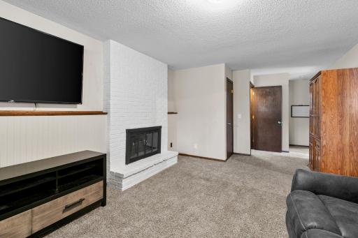 Cozy lower-level family room featuring a beautiful brick fireplace, spacious layout & the perfect spot to relax!