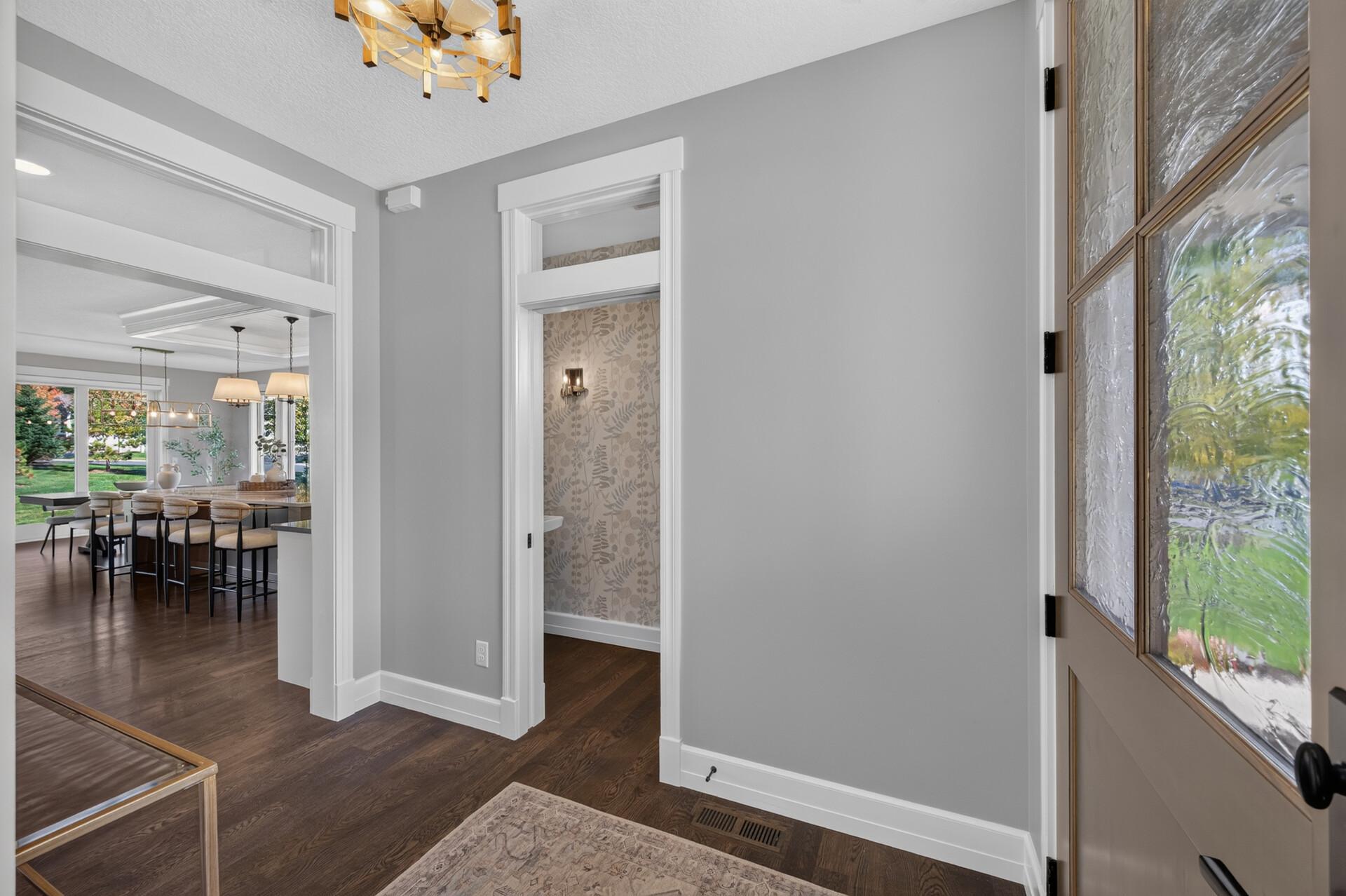 Main Level Half Bath sits adjacent to the Great Room, Kitchen, and Dining Room. Main Level boasts beautiful white oak hardwood flooring.