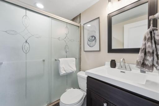 Bath with glass-door shower, matching fixtures, and elegant vanity