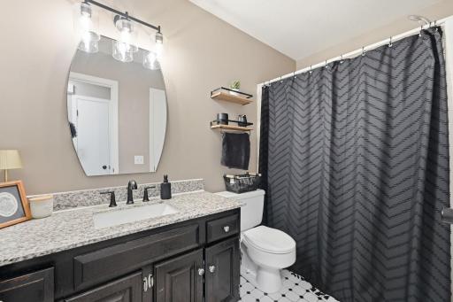 Updated main level full bath with granite vanity, matching fixtures, and updated trim, mirror, and lighting
