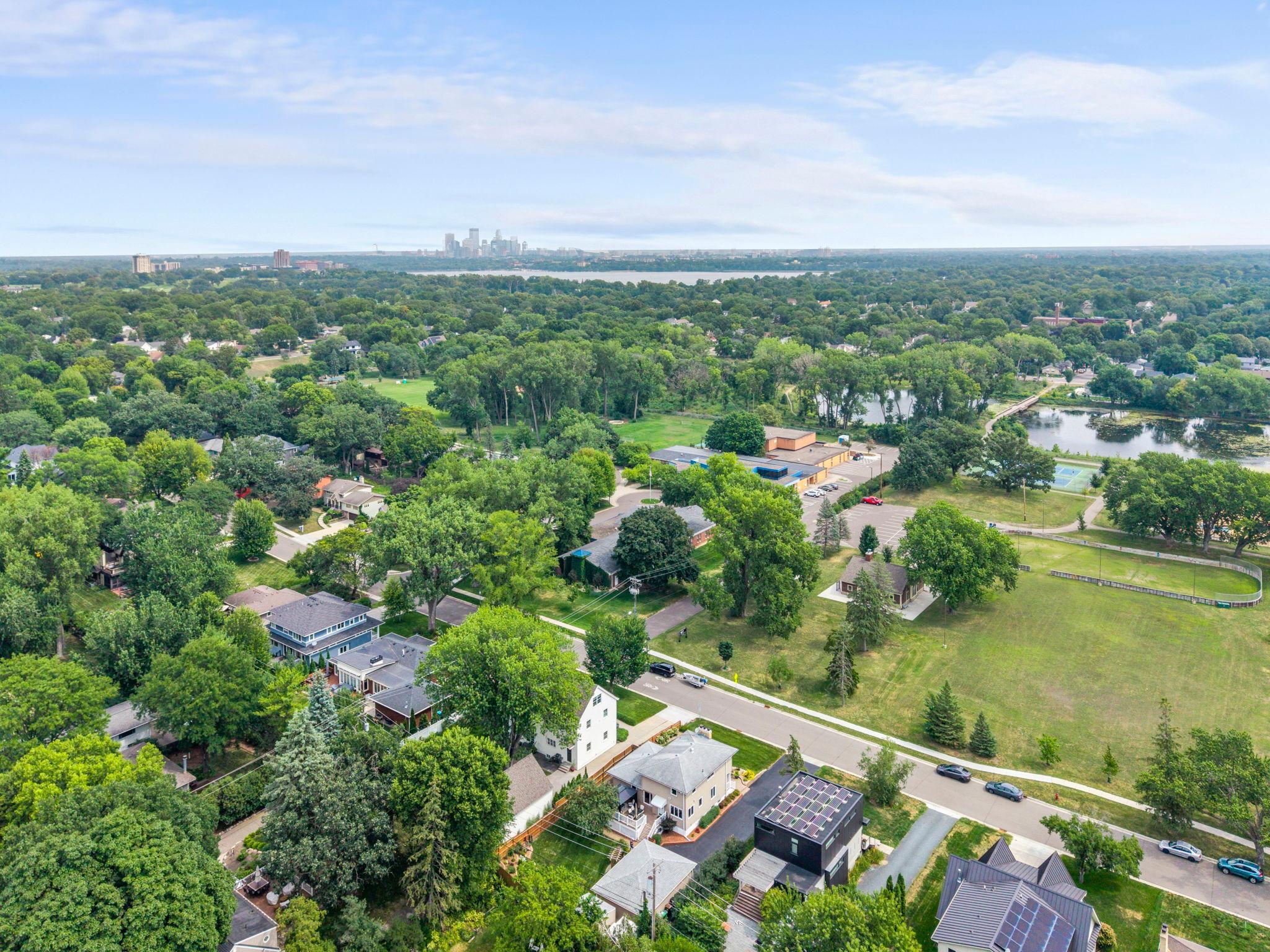 A stunning aerial perspective showcases the neighborhood's tree-lined streets with the downtown Minneapolis skyline on the horizon.
