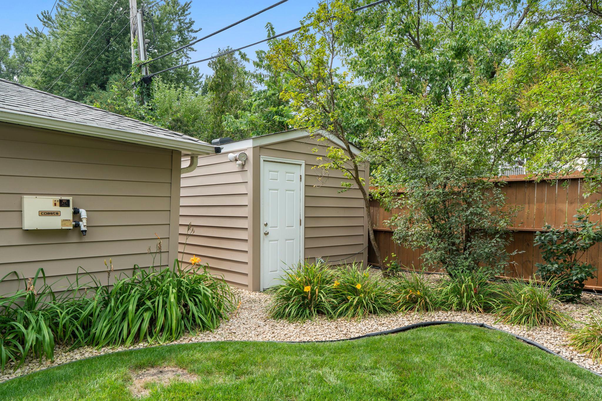 The detached garage's rear workshop entrance opens to landscaped side beds along the fence line.