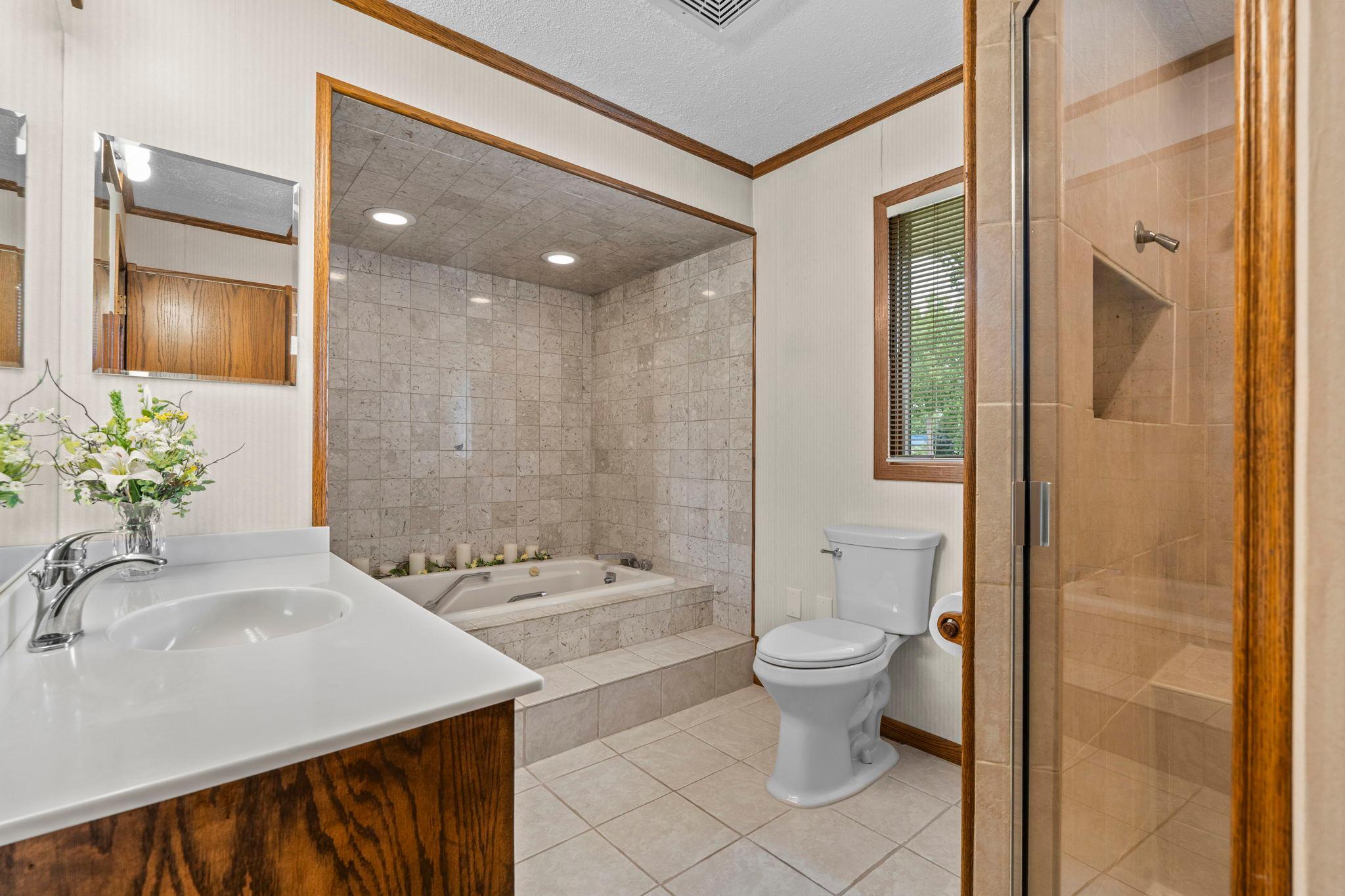 The primary bath features a soaking tub, separate glass shower, and a large vanity.