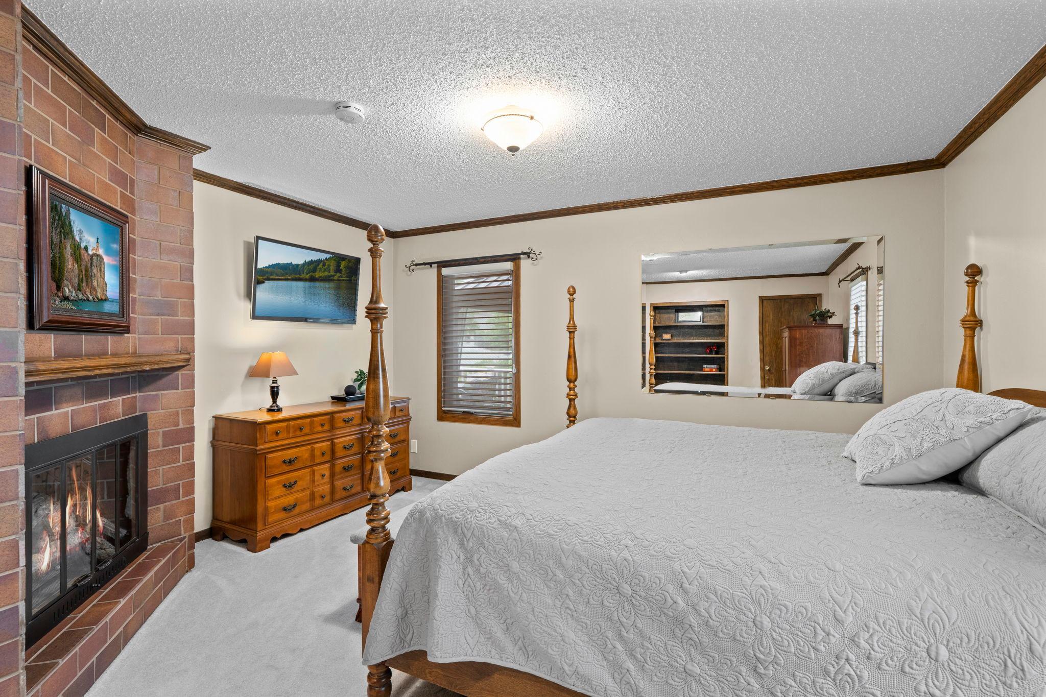 This bedroom's brick fireplace adds cozy character, one of three fireplaces found throughout the home.