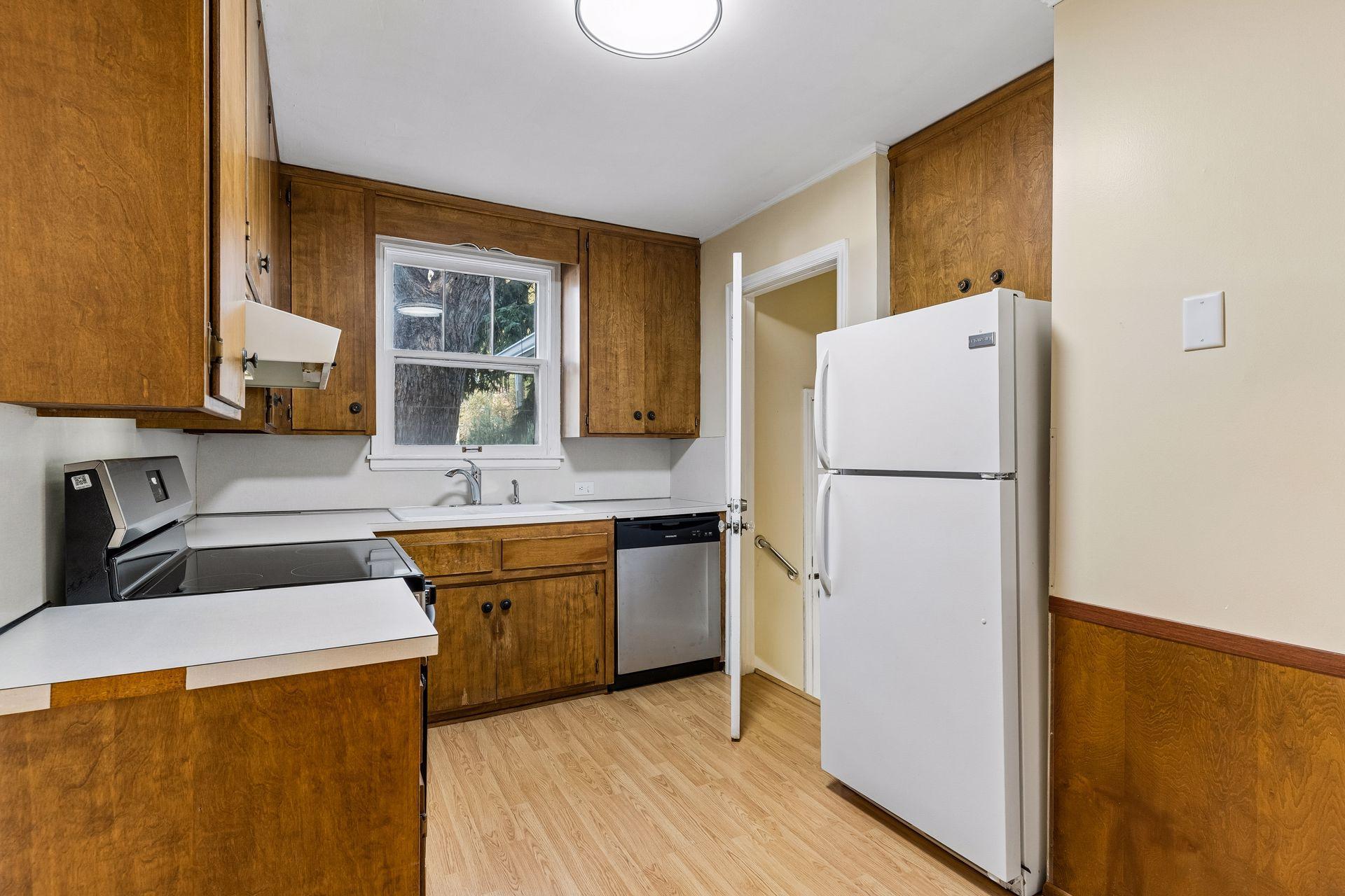 This tidy kitchen has a brand-new dishwasher and brand-new range. The stairs lead down to the basement.