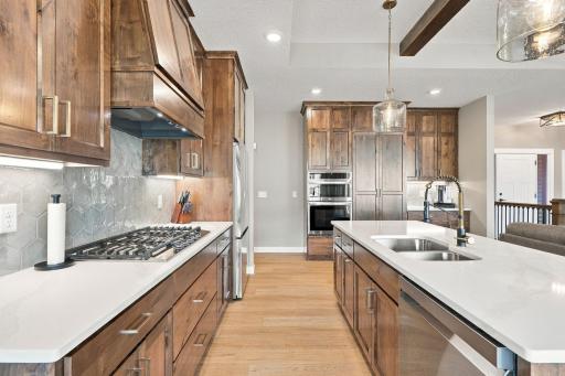 Gourmet Kitchen w/ knotty alder cabinetry to the ceiling, quartz countertops, oversized island, gas cooktop, wall oven & custom hood