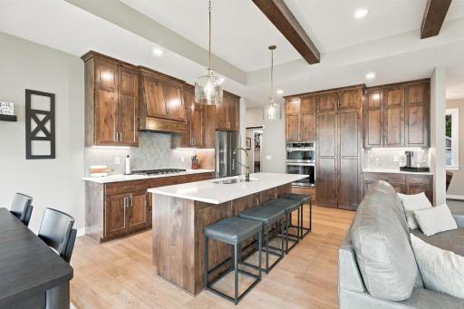 Gourmet Kitchen w/ knotty alder cabinetry to the ceiling, quartz countertops, oversized island, gas cooktop, wall oven & custom hood