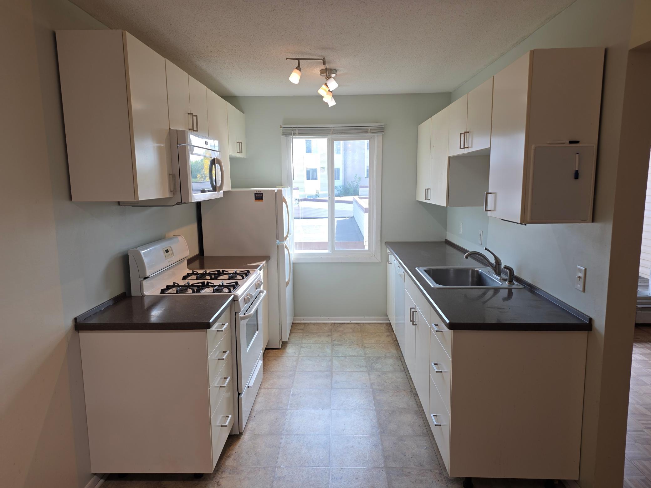 Galley kitchen with large window and eat in area