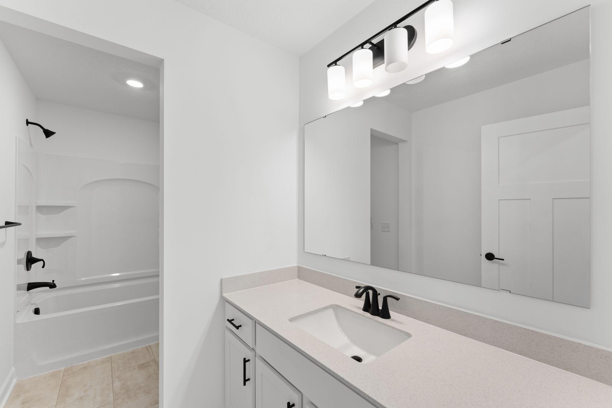 This full-sized bath features a wide vanity, designer cabinetry and a shower-tub combination.