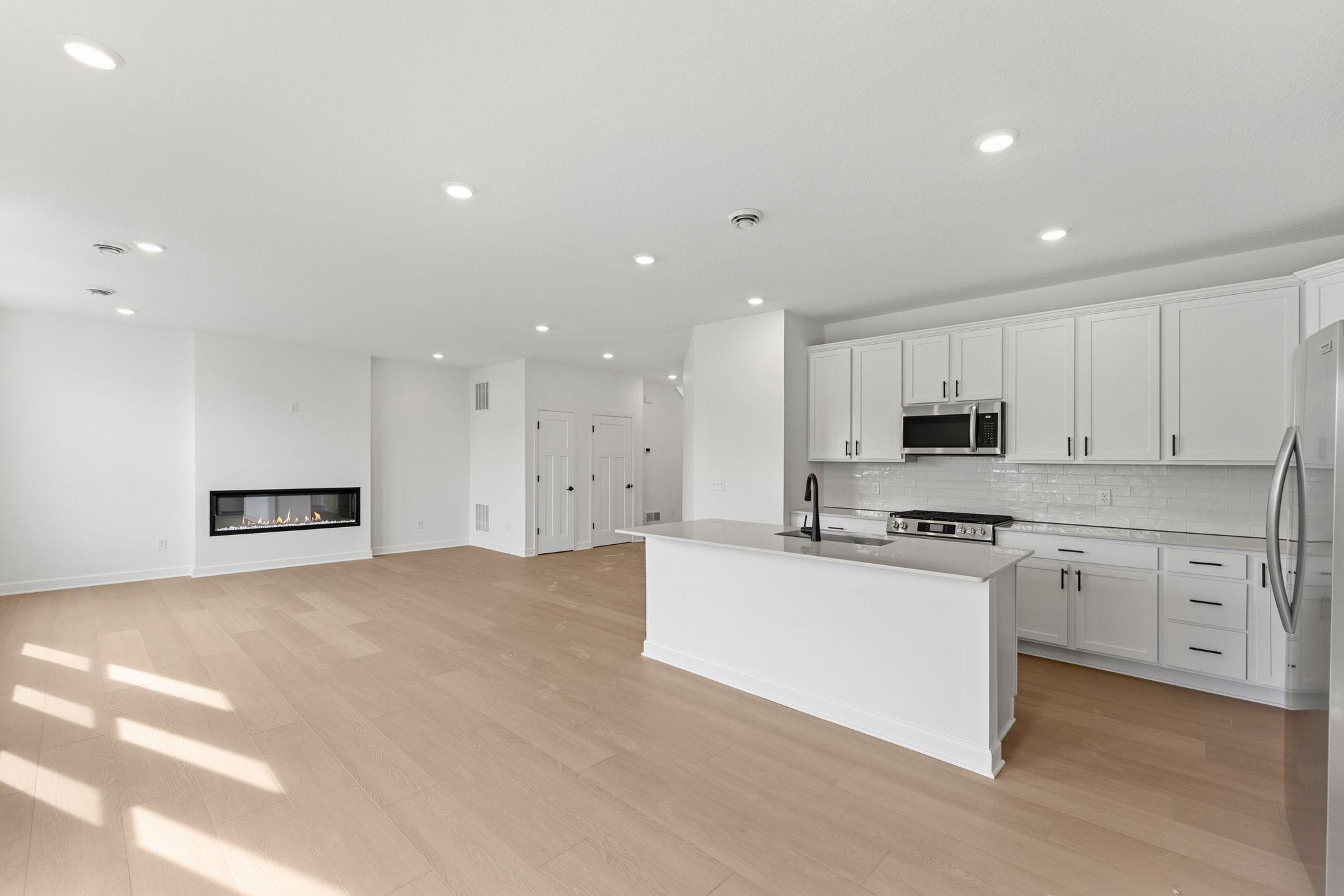 The center island features a stainless steel sink with a designer faucet while a modern dishwasher is within easy reach