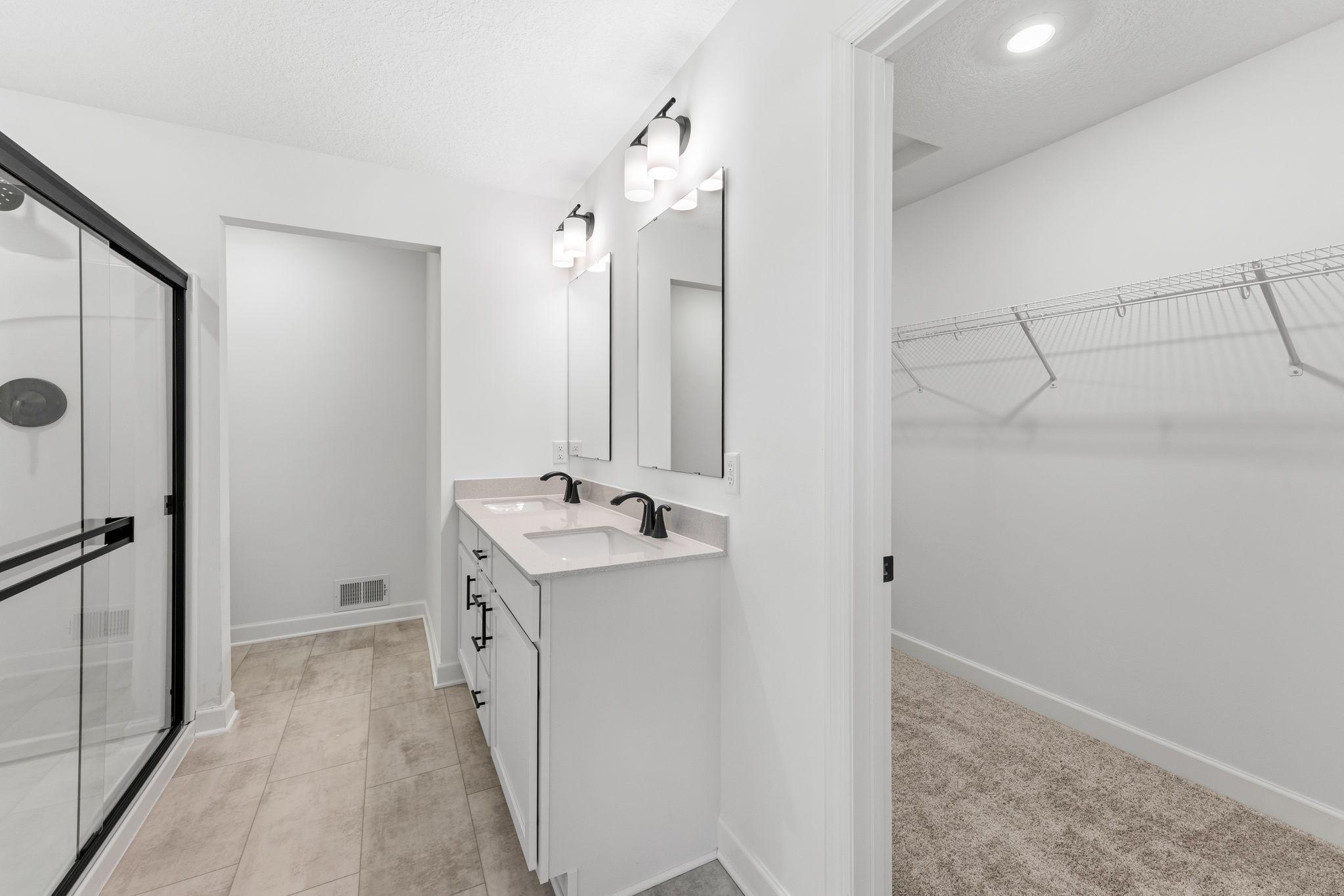 The en-suite bathroom features a glass-enclosed shower with a fiberglass surround