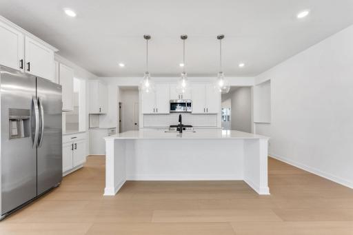 (All the following photos are of a similar home, actual finishes may vary.) The kitchen features a fluid open-concept layout that is ideal for preparing meals, complemented by a multifunctional center island and quartz countertops.