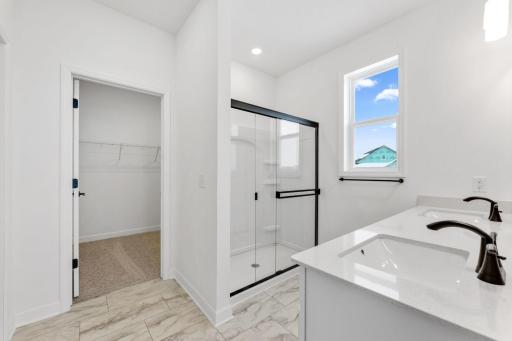 Featuring a dual-sink vanity, a glass-enclosed shower and direct access to the walk-in closet, the en-suite bathroom streamlines morning routines