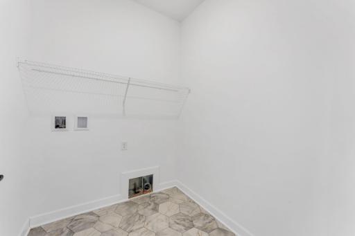 Laundry made easy with this convenient laundry room featuring ventilated shelving.