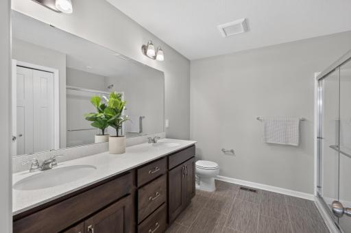 Timeless features decorate the primary en suite bath, with ample storage space, beautiful tile, and dual vanity.
