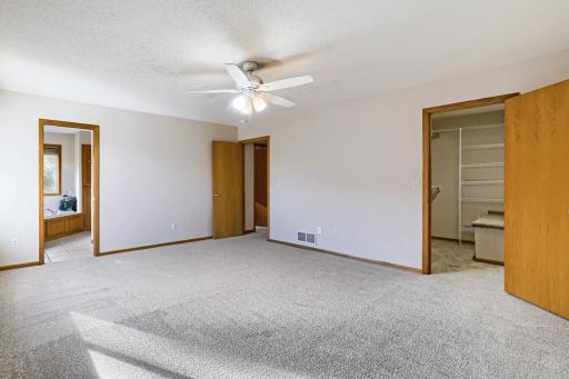 Spacious primary bedroom with new wall-to-wall carpet, neutral fresh paint, and warm oak trim throughout. Private full bath and a generous walk-in closet with built-in storage. Ceiling fan for year-round comfort. Clean, bright, and move-in ready.