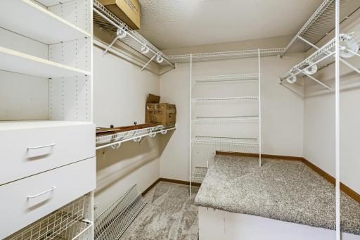 Spacious walk-in closet offers exceptional storage with abundant shelving, hanging space, built-in drawers, and a convenient center island for additional organization. Plenty of room to keep everything neatly organized!