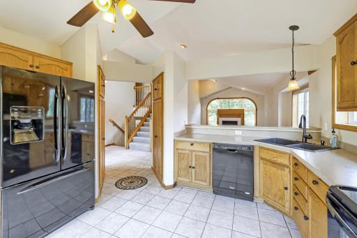 Bright and spacious kitchen features beautiful oak cabinetry, generous counter space, black appliances, and easy-care tile flooring. The convenient breakfast bar opens to the family room, creating a wonderful flow for everyday living and entertaining
