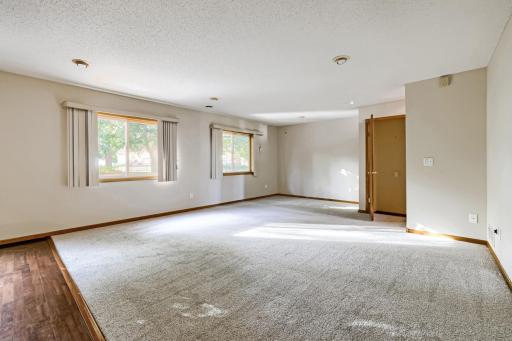 Another view of the lower-level family rm showcases the abundance of natural light streaming through multiple windows, fresh neutral paint, and new carpeting. A doorway leads to an additional finished 4th level, providing even more versatile living!