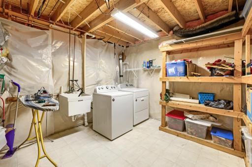 Spacious laundry and storage room features a washer and dryer, convenient utility sink, and extensive built-in shelving for all your storage needs. Plenty of room to keep everything organized, with additional space for household supplies & seasonalal