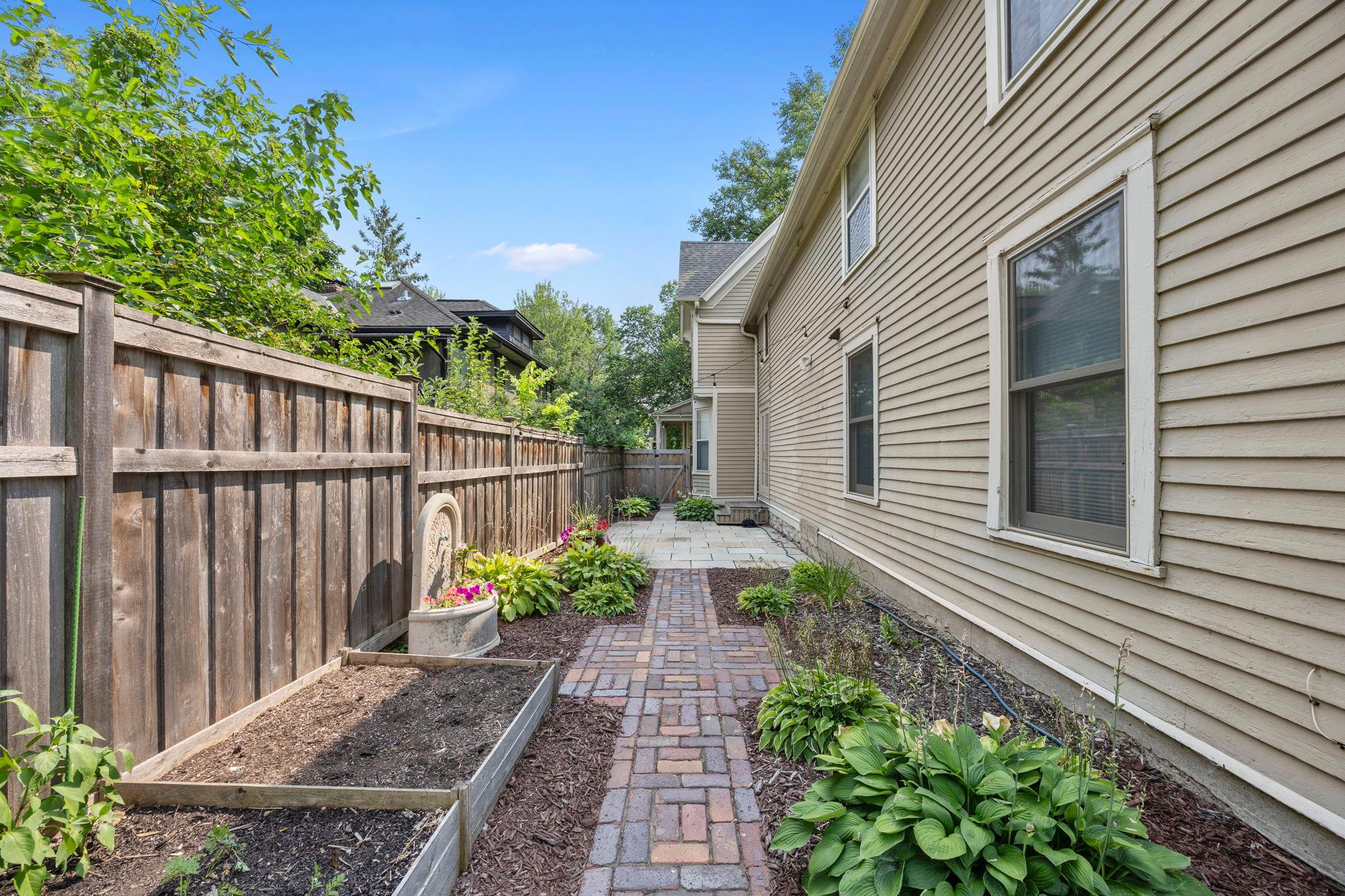 A paved path from the patio leads to a charming garden area.