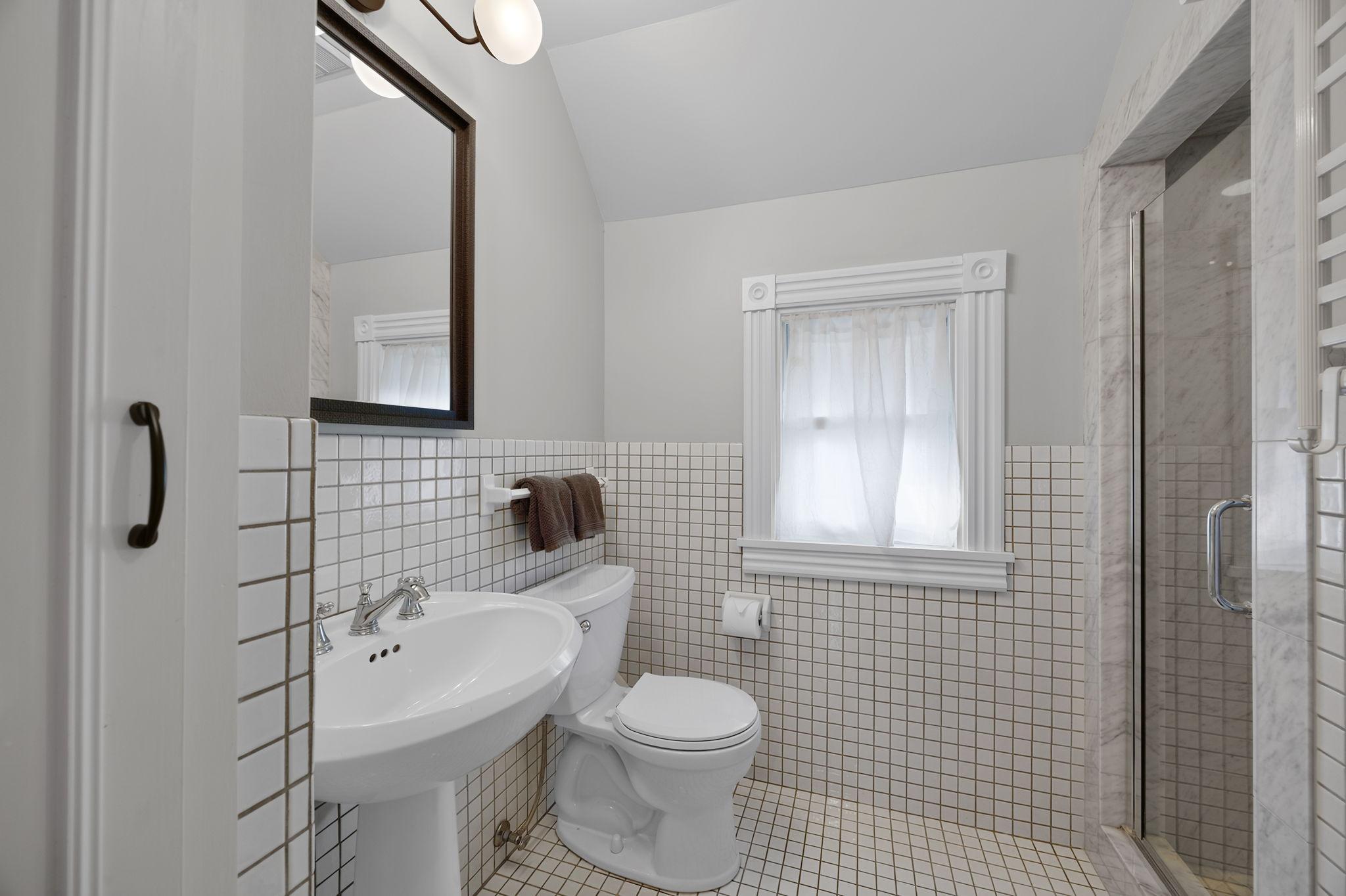 Conveniently located just steps from all four bedrooms, the shared ¾ bathroom offers tile flooring, a pedestal sink, and a tiled walk-in shower.