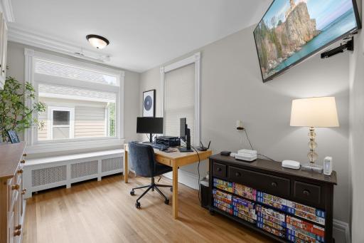 The main level also features a versatile office or flex space with warm wood floors, large side and rear windows, and built-in cabinetry, creating an ideal work-from-home environment.