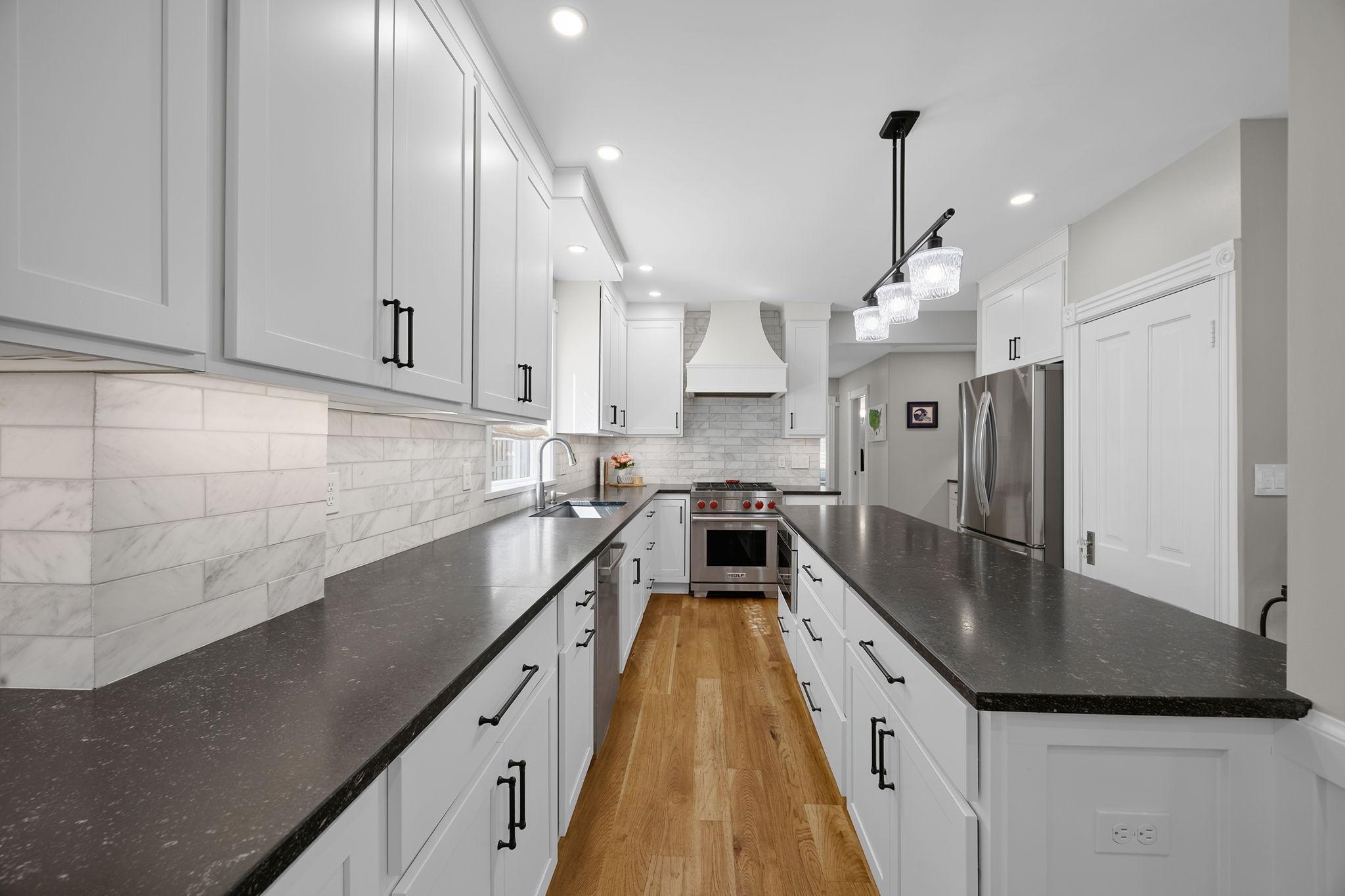 The stunning chef’s kitchen has been completely remodeled and features expansive granite countertops, a spacious center island, abundant white cabinetry, stylish backsplash, and stainless steel appliances, including a Wolf dual fuel cooktop & range.