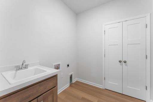 The laundry room comes complete with laundry sink and cabinet. Additional closet provides storage for coats & shoes. Similar home shown. Color and options can vary.