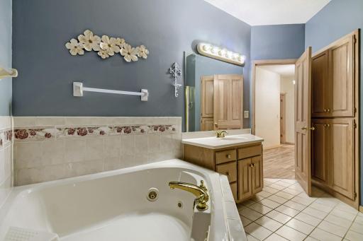 Primary walk-through bathroom with corner jetted tub and separate shower.