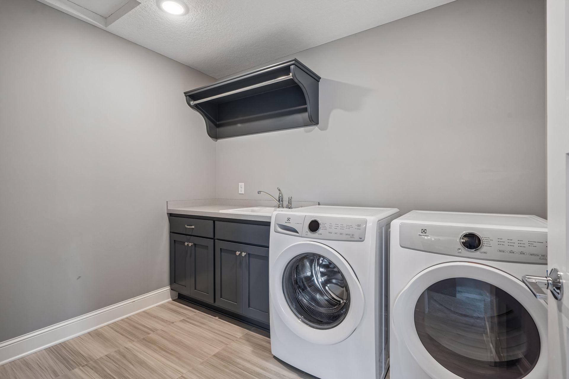 A spacious upper-level laundry room with utility sink and cabinetry adds everyday convenience.