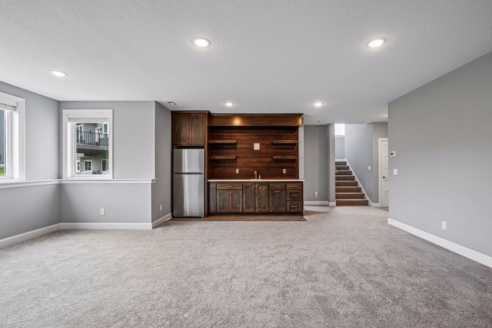 A striking wet bar with rich dark wood cabinetry, beverage refrigerator, and open shelving!