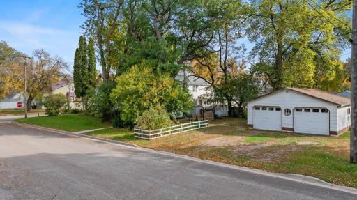 The back side of the property shows the detached 2 stall garage, concrete sidewalk leading to the rear breezeway, and mature trees offering a semi private backyard