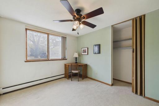 Second Bedroom: Versatile second bedroom featuring a large window, ceiling fan, and spacious closet, perfect for guests or a home office.