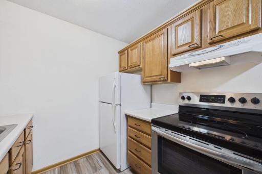 Functional kitchen featuring classic oak cabinetry, generous storage, ample countertop space, and stainless steel electric range.