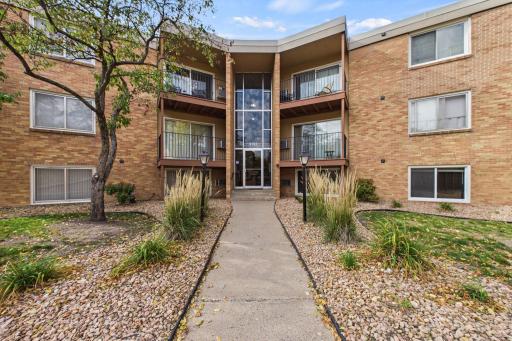 Building Exterior: Welcoming brick condominium building featuring a beautifully landscaped entrance, mature trees, and inviting common areas.