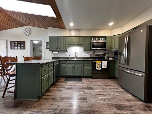Love the Beautiful Spacious Kitchen with Green Cabinets, White Backsplash and Stainless Steel Appliances!