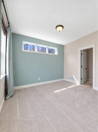 Bright and spacious office with soft neutral finishes, a calming accent wall, and high transom windows that provide natural light and privacy.
