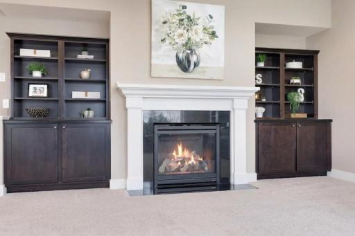 Inviting living room focal point featuring a cozy fireplace with crisp white surround, dark tile accents, and built-in cabinetry and shelving for added character and storage.