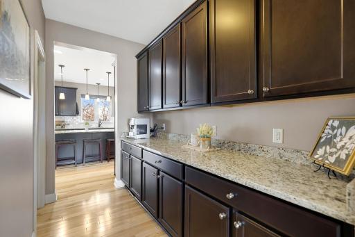 Generous butlerâs pantry provides abundant cabinetry and granite counter space, offering convenient additional storage and a functional connection to the kitchen.