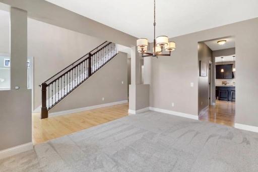 Spacious formal dining room featuring a stylish chandelier, neutral finishes, and an open layout with beautiful views of the staircase and easy access to the kitchenâan inviting space for everyday dining and entertaining.