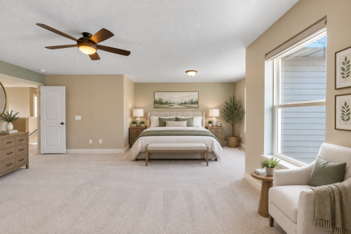 This spacious primary suite offers a relaxing retreat with generous room for a full bedroom set and sitting area, complemented by soft neutral finishes, abundant natural light, and a ceiling fan for added comfort.