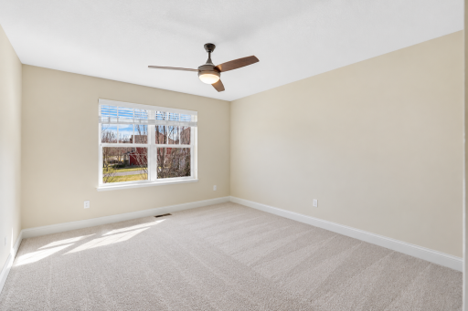Spacious upper-level bedroom featuring soft neutral finishes, abundant natural light, and a generous walk-in closet offering excellent storage.