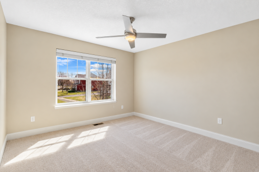 Bright and spacious fourth upper-level bedroom featuring neutral finishes, abundant natural light, a ceiling fan, and a generous walk-in closet for added storage.