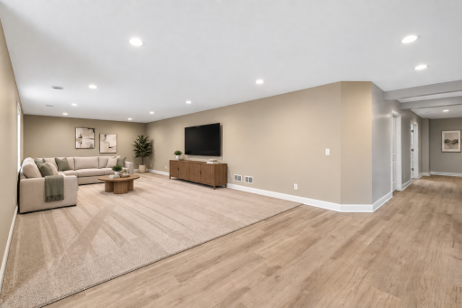 Expansive finished lower level offers plenty of room for movie nights, entertaining, or relaxing, with recessed lighting, a comfortable carpeted living area, and durable flooring throughout the adjoining hallway.