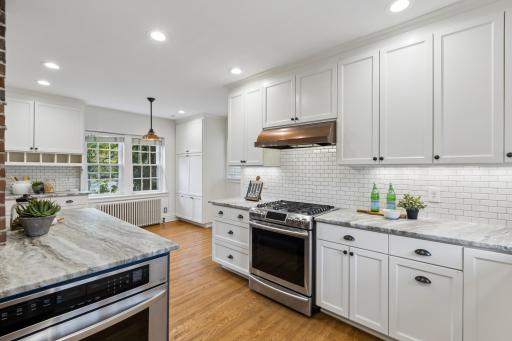 Gas range, subway tile backsplash and a wall oven built into the island