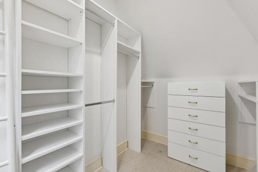 Walk-in closet with custom built-ins and loft above space