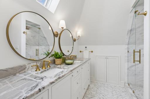 Remodeled ownerâs bath with double vanity, skylight and brushed-gold fixtures